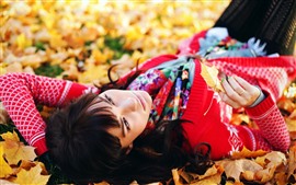 Fille dormir sur le sol, feuilles d'érable, automne